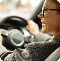 Woman holding a stirring wheel and looking to her left smiling