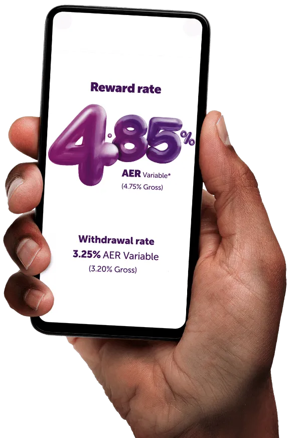 A hand holding a smartphone, showing the Atom Instant Saver Reward interest rates with reward rate 4.85% AER variable, 4.75% gross, and withdrawal rate 3.25% AER variable, 3.2% gross. Asterisk denotes there is text explaining the meaning of AER variable on the page