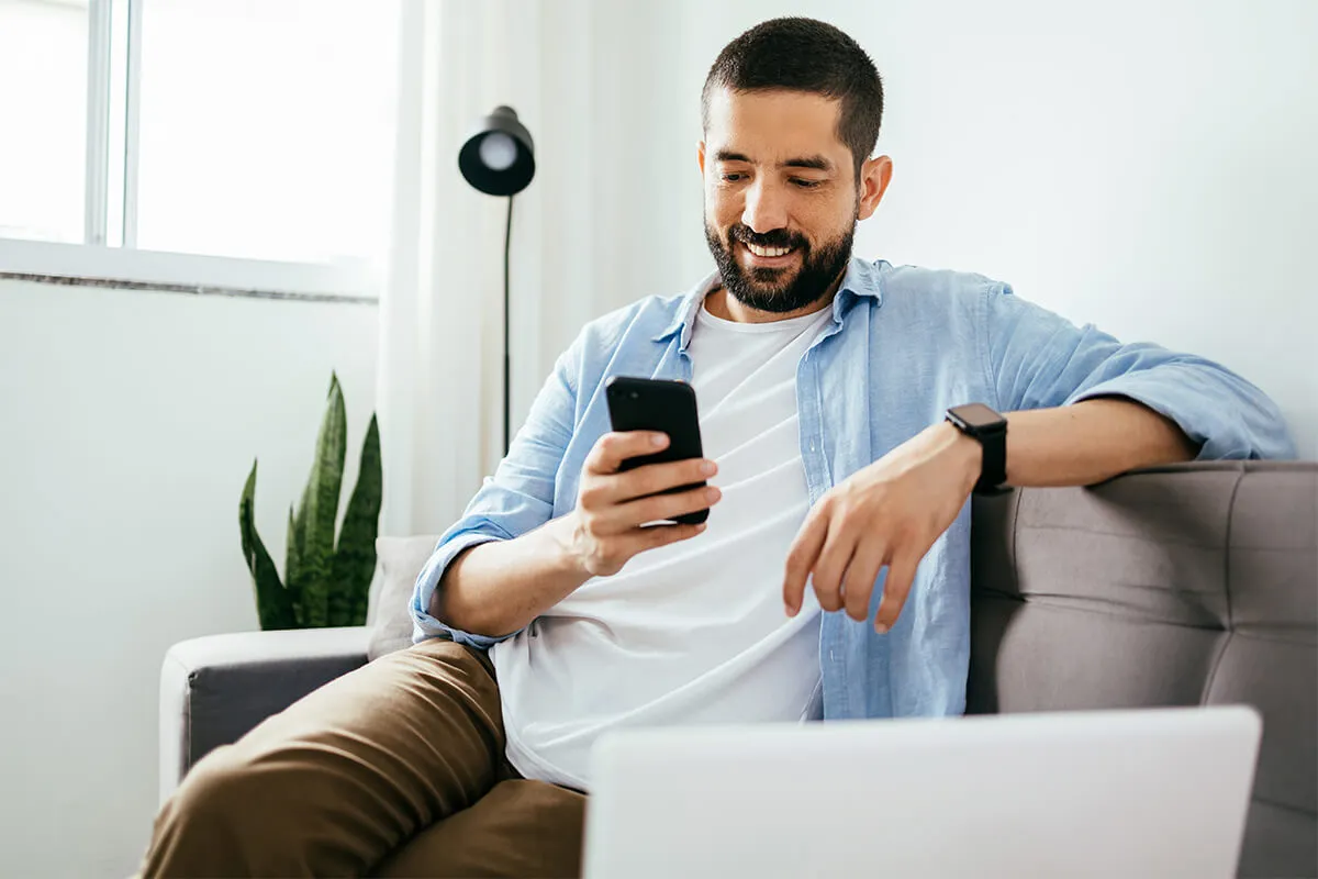 Person sitting on sofa looks at their phone and smile