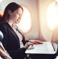 A woman is sat on a plane working on her laptop